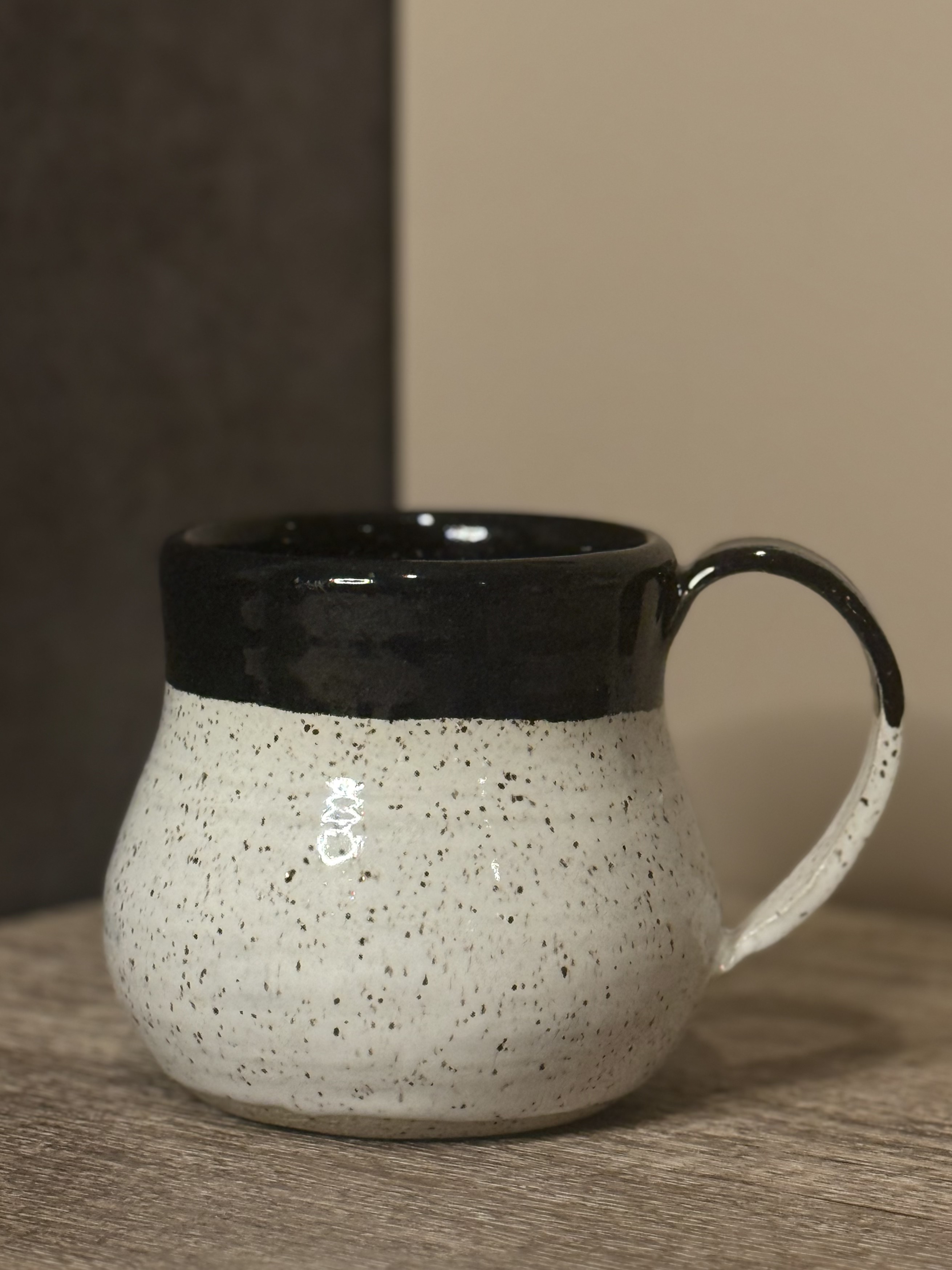Handmade speckled mug with dark navy rim and curved handle