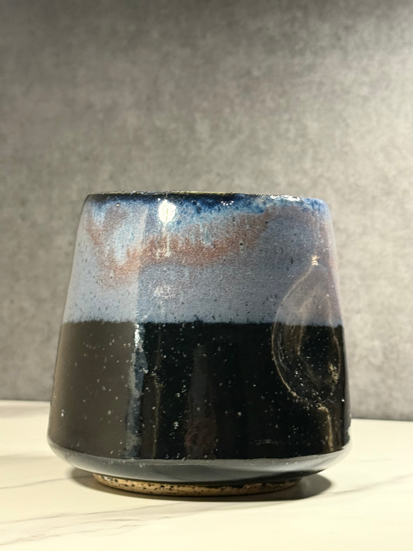 Tapered ceramic tumbler with periwinkle and dusty rose glaze fading into speckled glossy black
